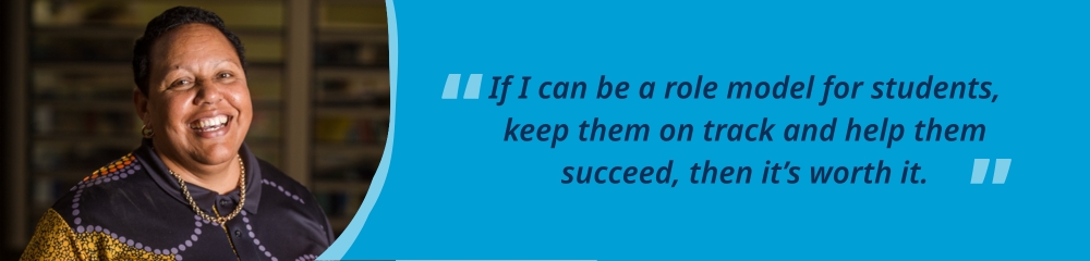 Amanda standing and smiling in a classroom, accompanied by the quote, “If I can be a role model for students, keep them on track and help them success, then it’s worth it.”