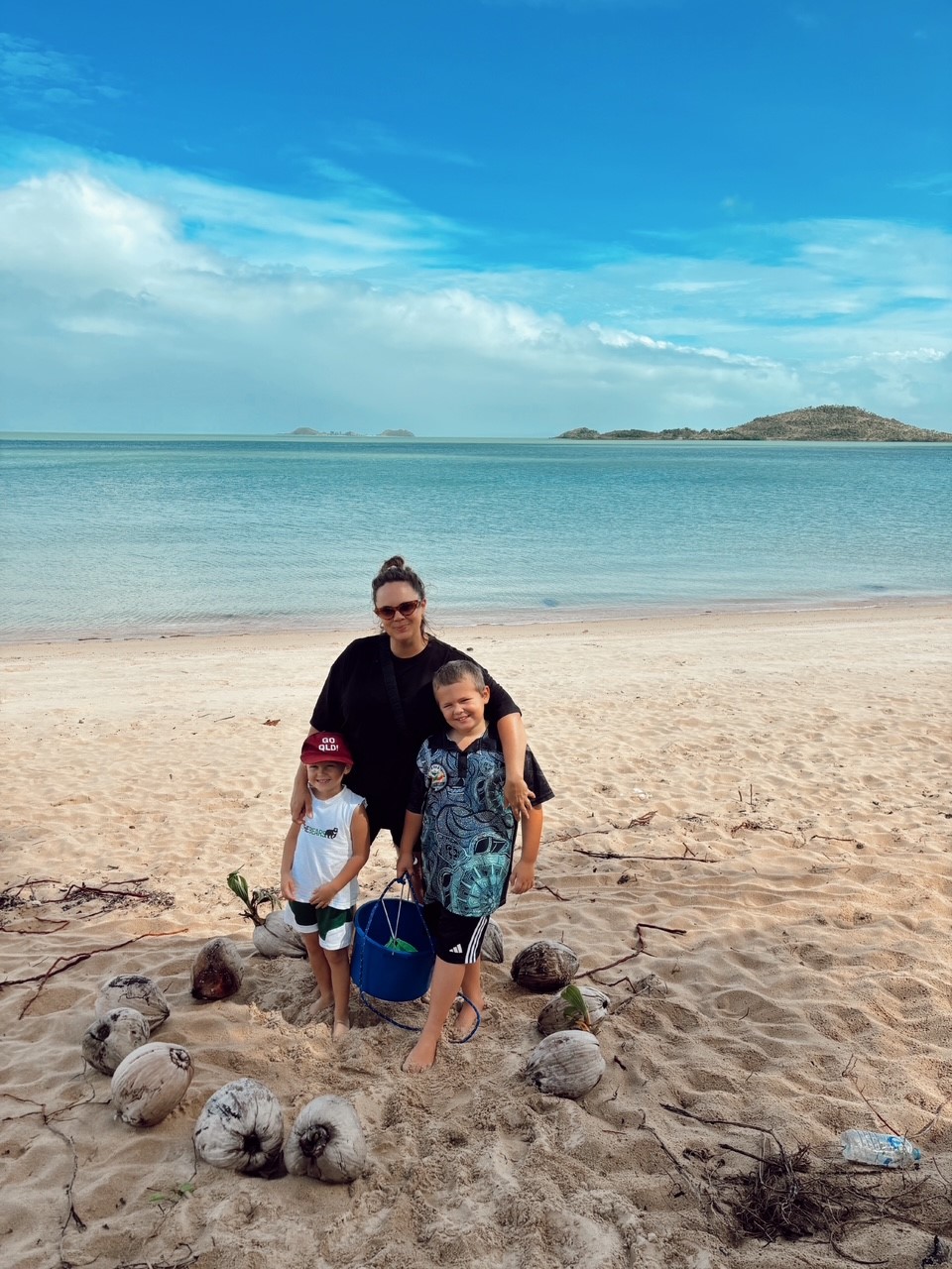 Bella and her two children standing on a beach.