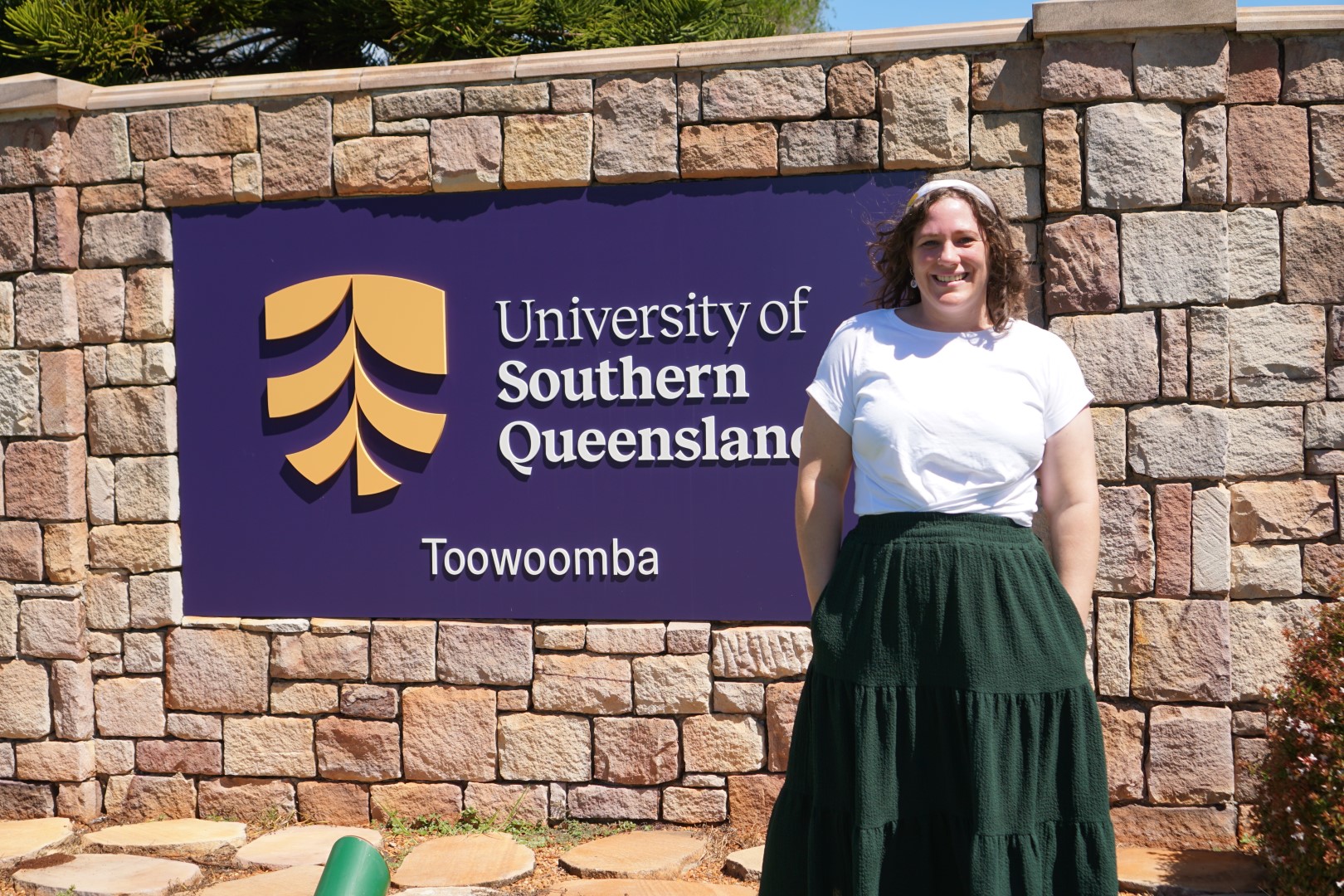 Kelly standing in front of a University of Southern Queensland sign.